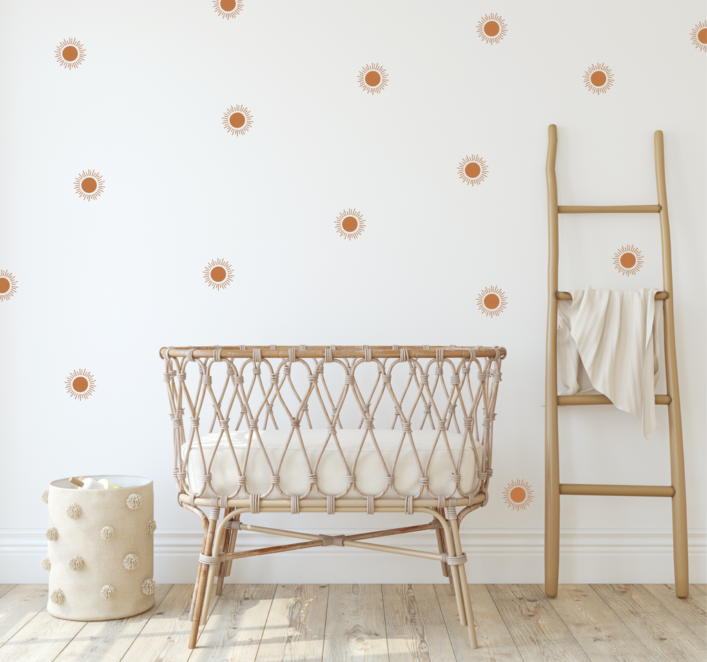 boho nursery with terracotta sun stickers and a canopy over a baby bassinet