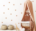 neutral nursery with terracotta sun wall decals behind a rattan crib