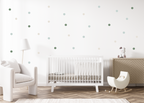 Pastel green and beige dot decals arranged on a clean nursery wall above a crib and wooden cabinet