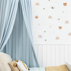 Neutral safari animal decals, rainbows and stars decorating a kids’ room wall beside a blue canopy and bed