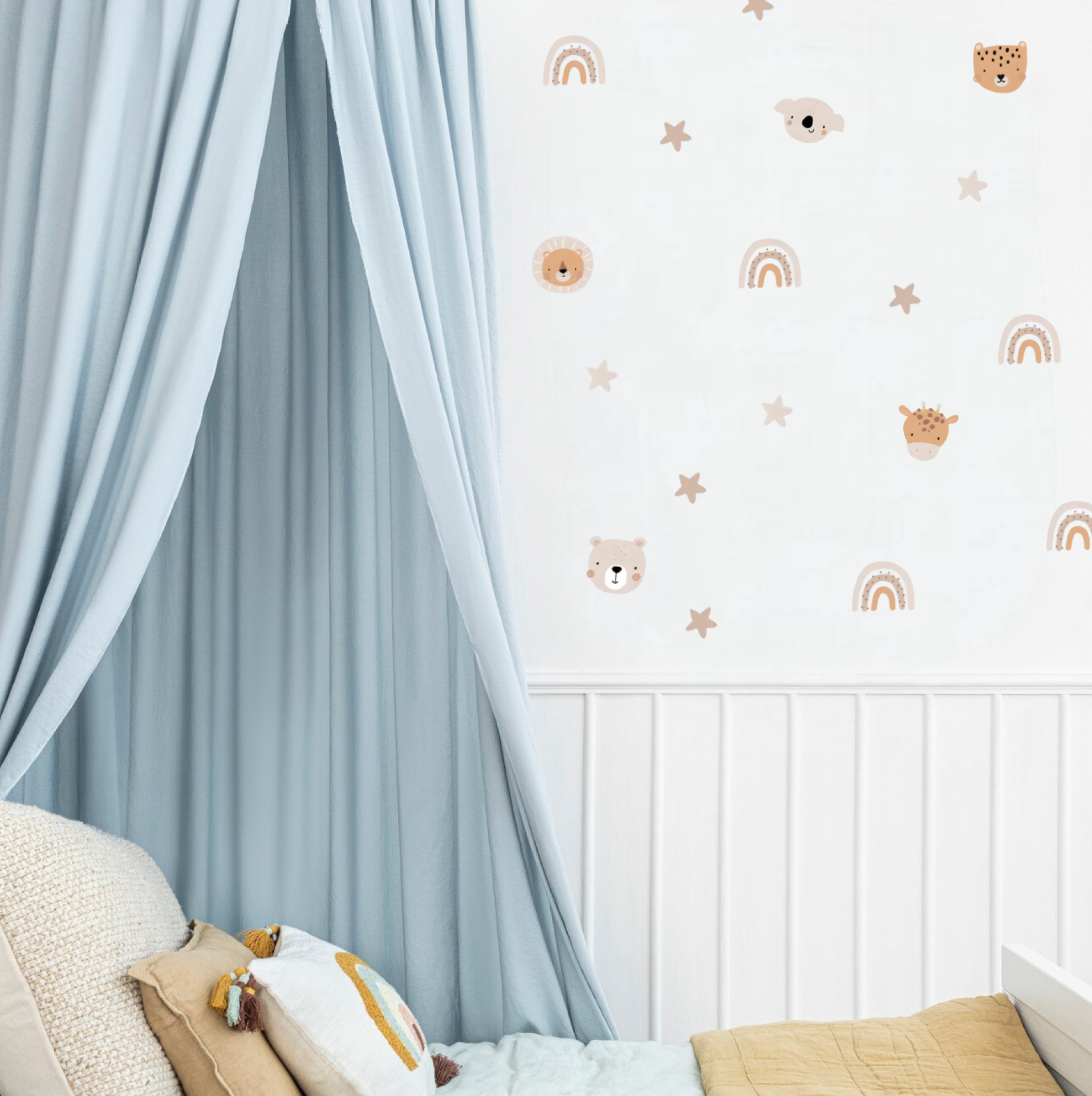 Neutral safari animal decals, rainbows and stars decorating a kids’ room wall beside a blue canopy and bed