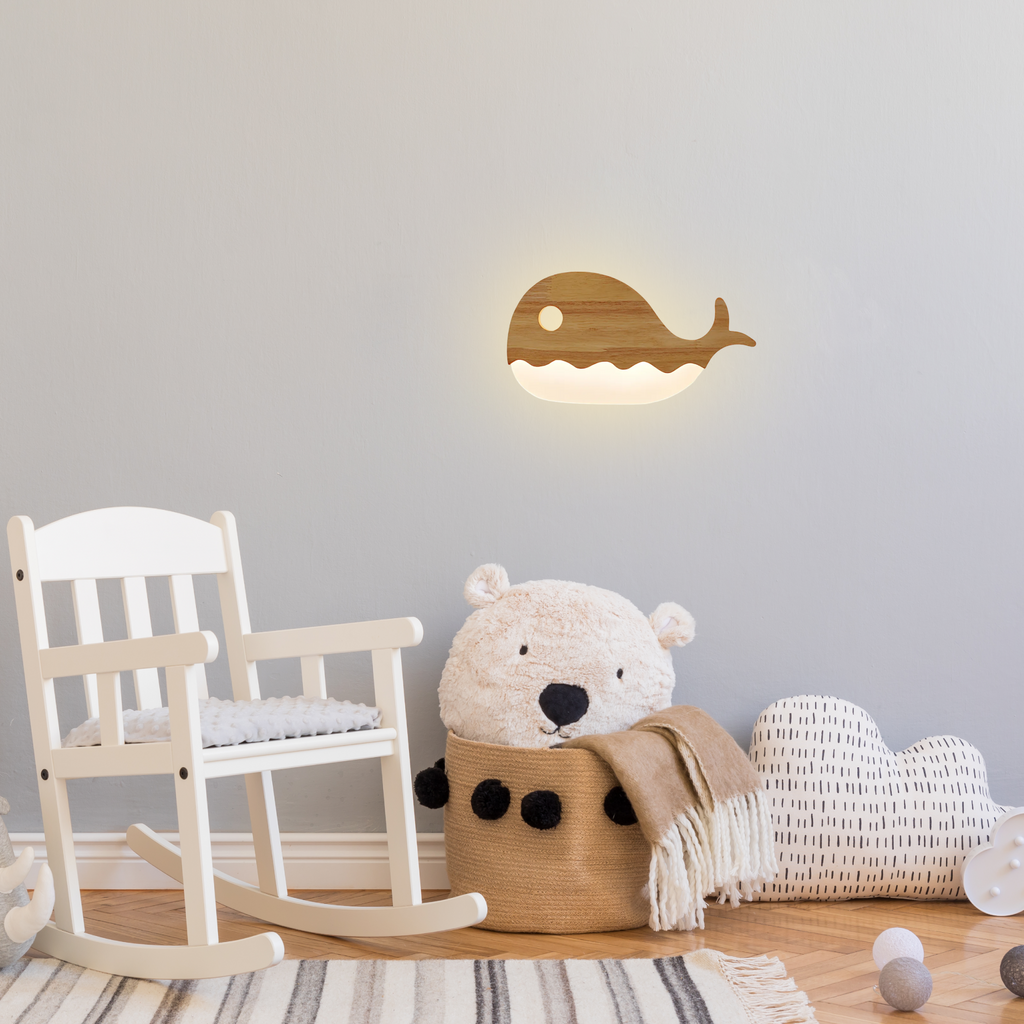 Whale-shaped wooden LED wall lamp glowing softly in a cozy kids’ room